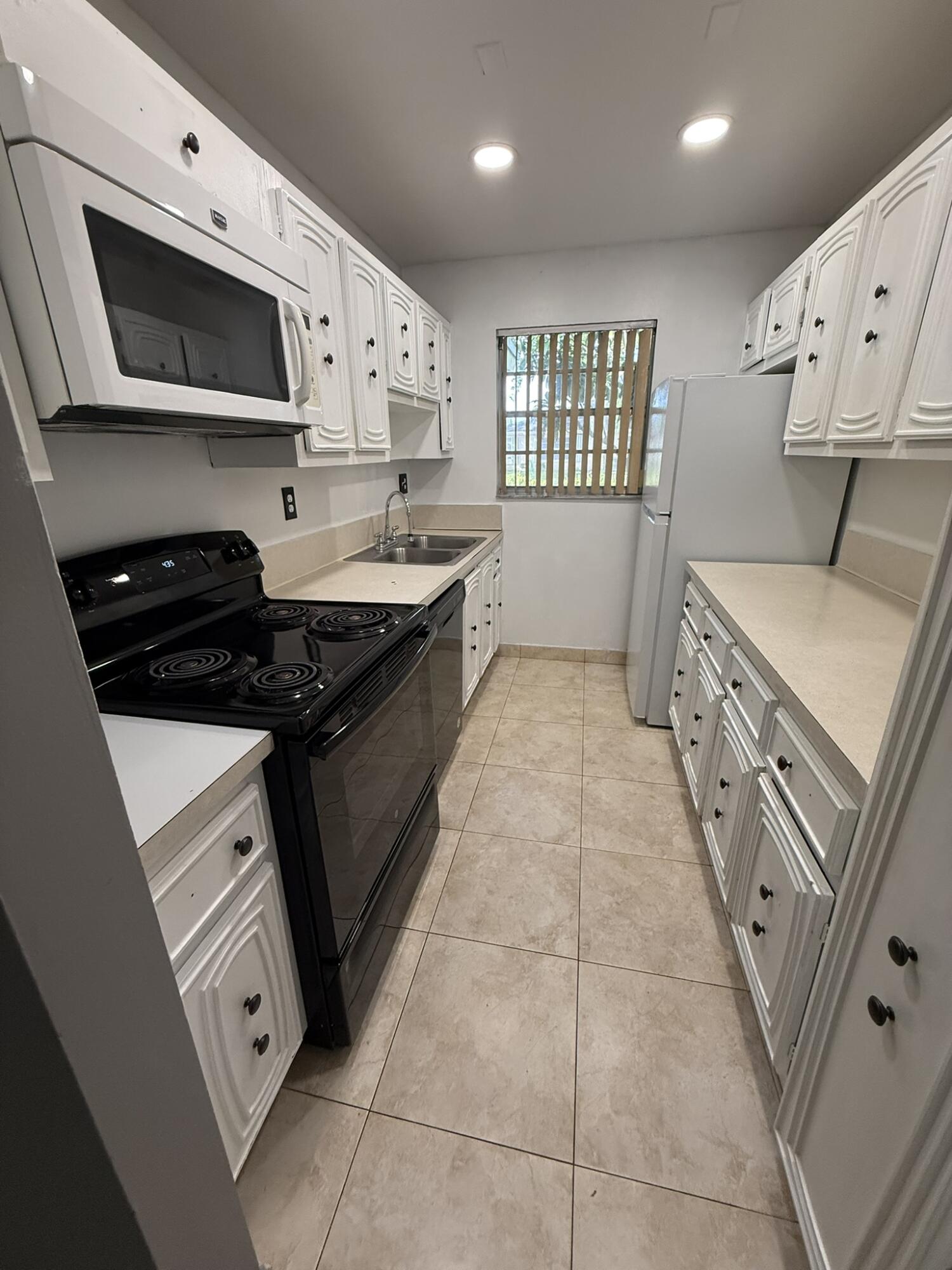 Galley Kitchen with microwave, stove, oven and dishwasher.