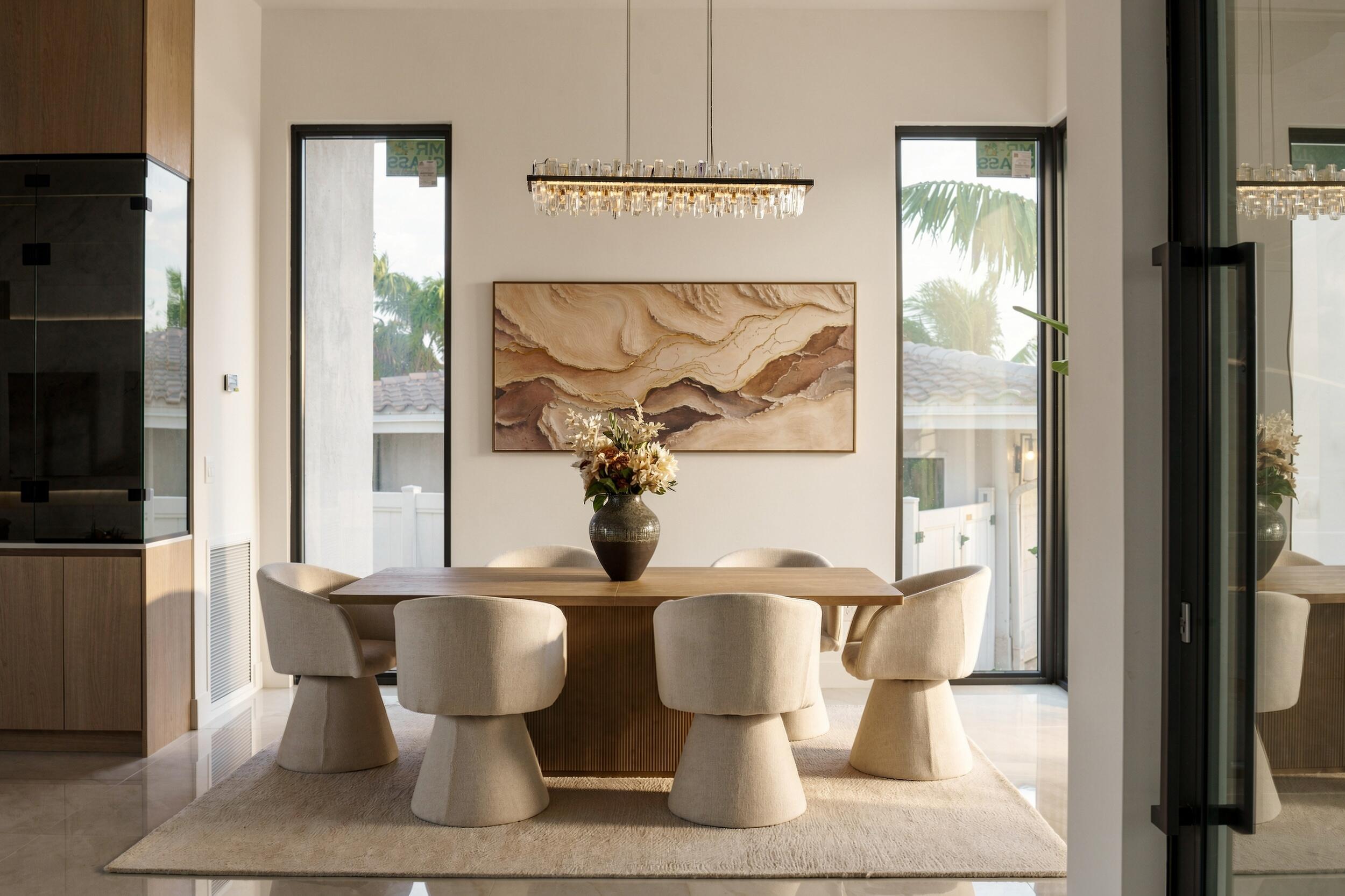 Dining area featuring floor-to-ceiling windows, custom built-in cabinetry, polished stone flooring, and a linear crystal chandelier