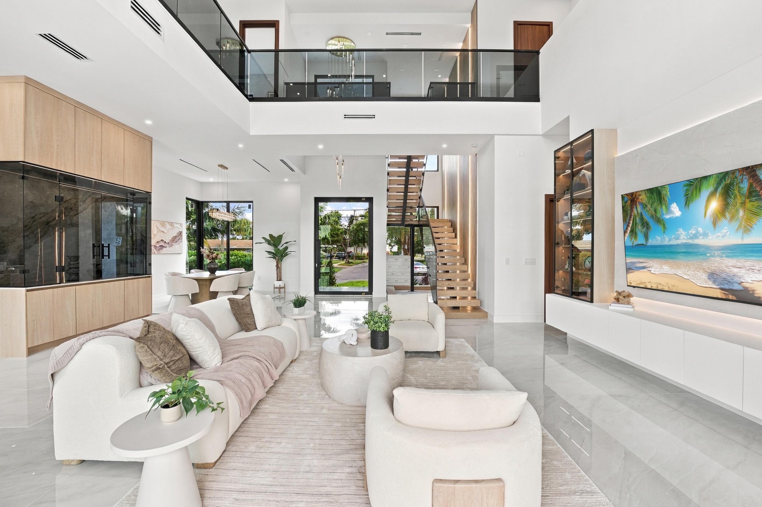 Double-height living area featuring floor-to-ceiling cabinetry, a floating staircase with glass balustrades, large-format tile flooring, and integrated media wall cabinetry
