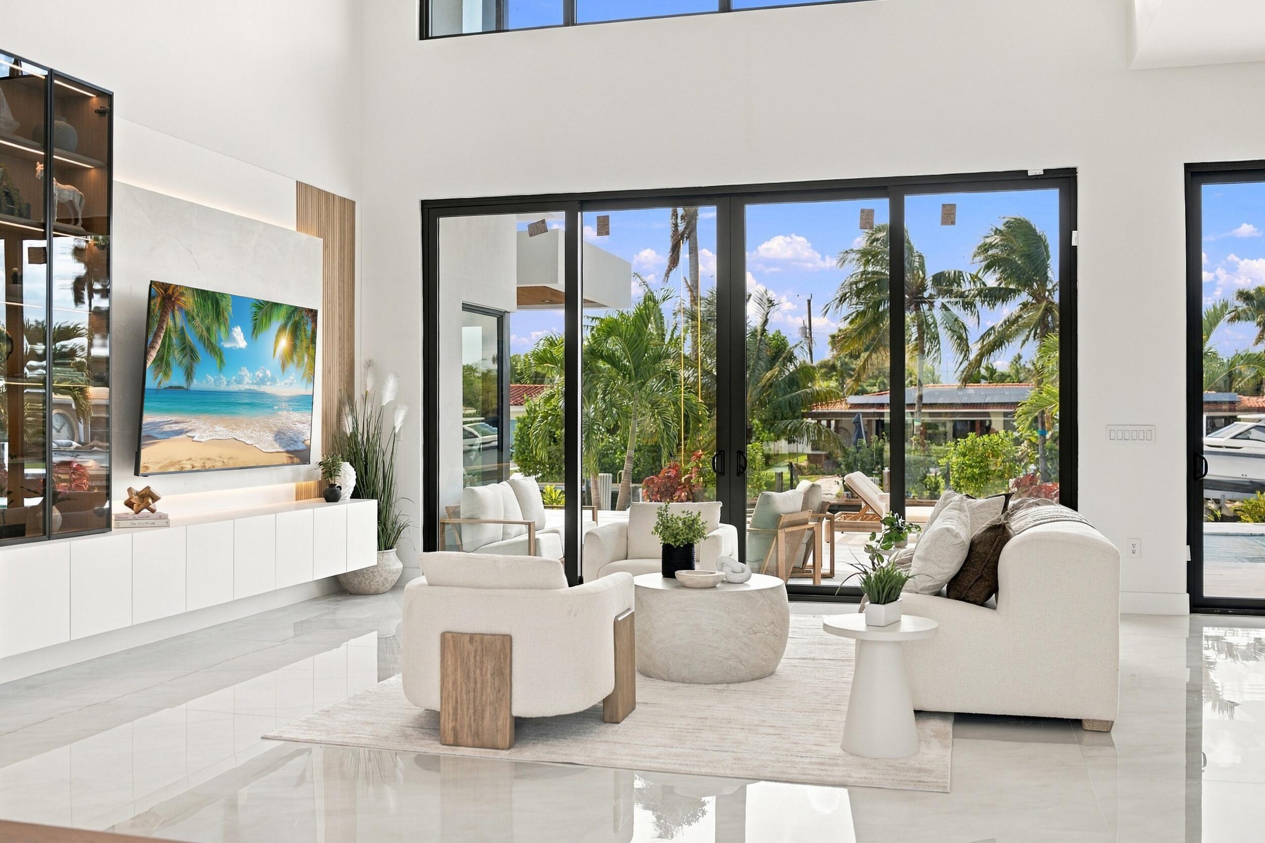 Double-height living area featuring floor-to-ceiling glass sliding doors, stone-finish flooring, and built-in minimalist cabinetry with recessed lighting