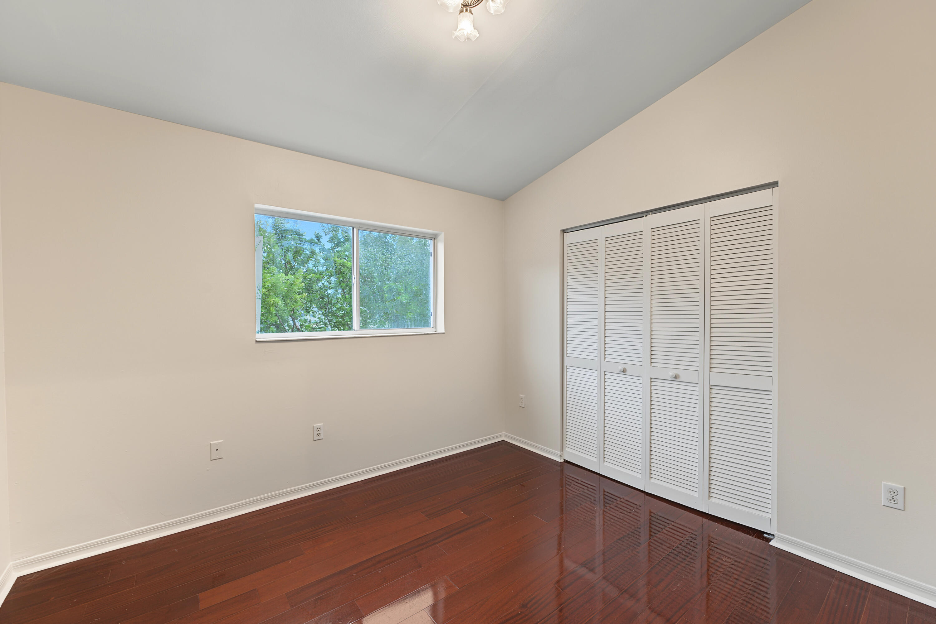 Vaulted ceilings, wood-finish flooring, and white louvered-style closet doors