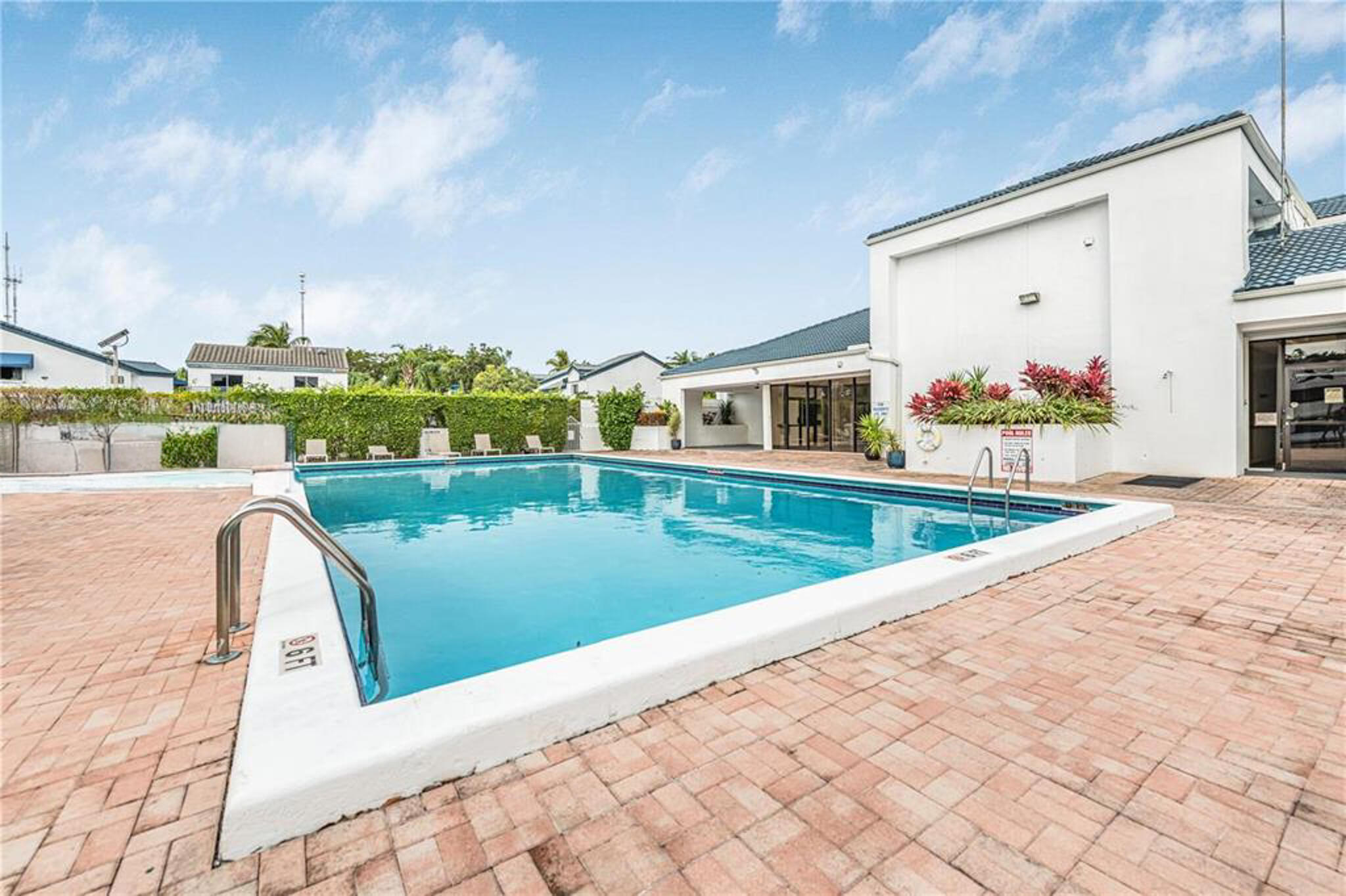 Swimming pool featuring brick paver decking, metal entry rails, and integrated landscape planters