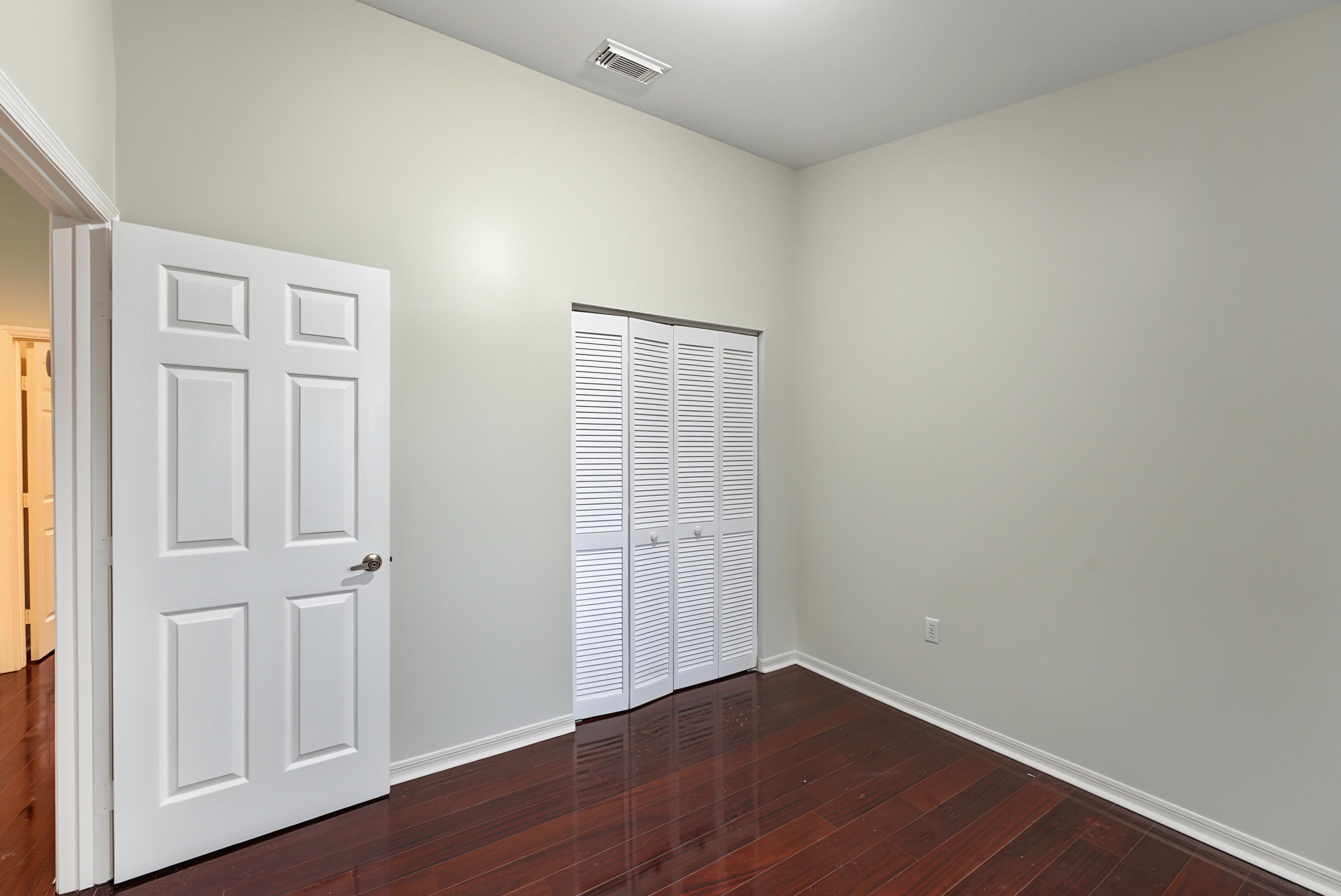 High ceilings, wood-finish flooring, and white louvered bifold closet doors