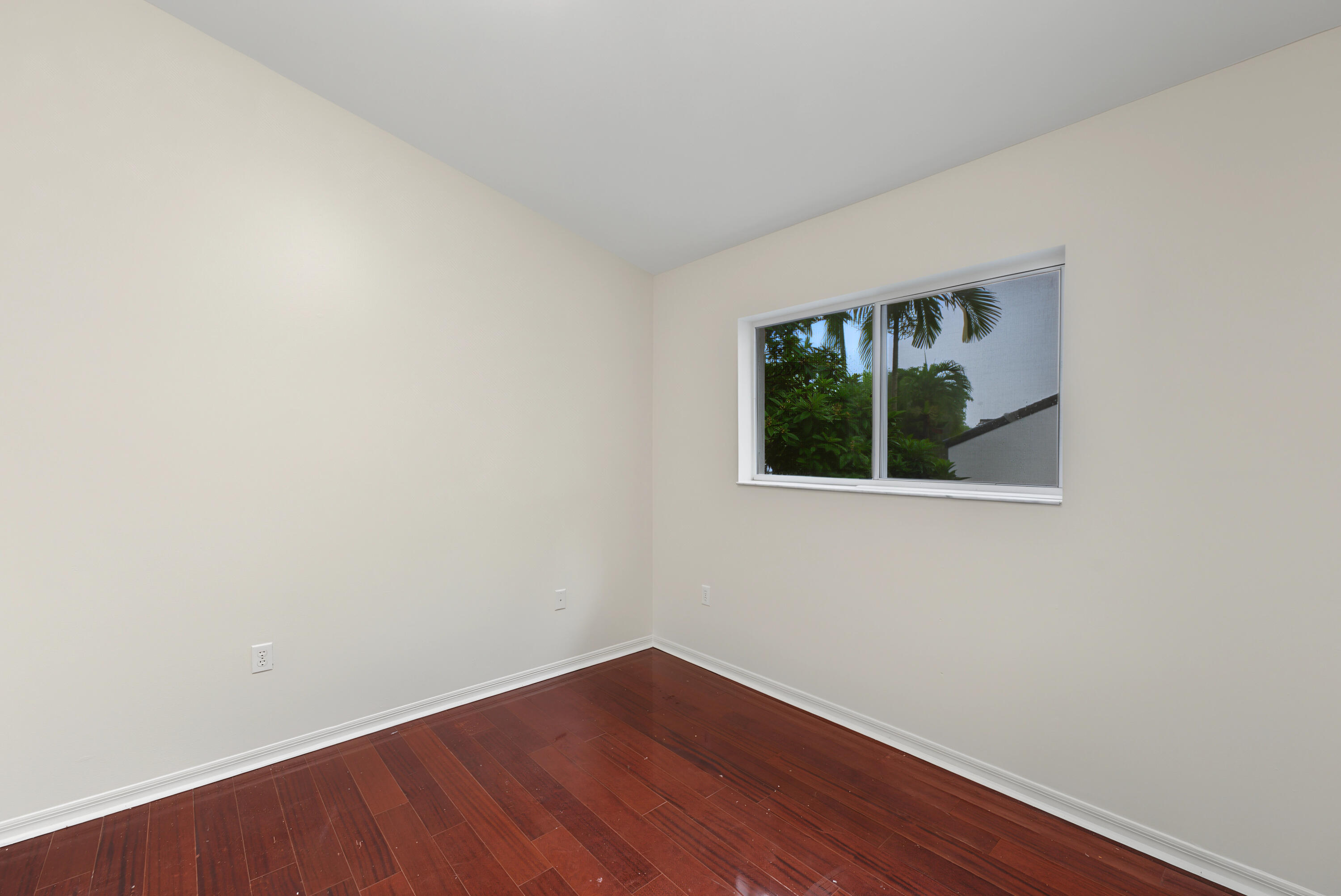 Neutral-toned interior space featuring wood-finish flooring and a single horizontal sliding window