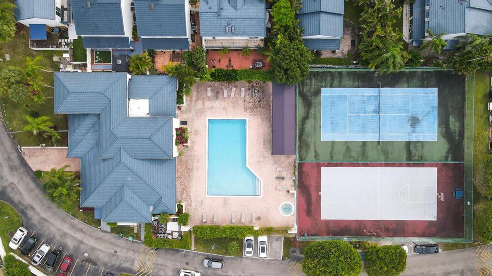 Aerial perspective featuring a swimming pool, spa, fenced tennis court, and outdoor basketball court