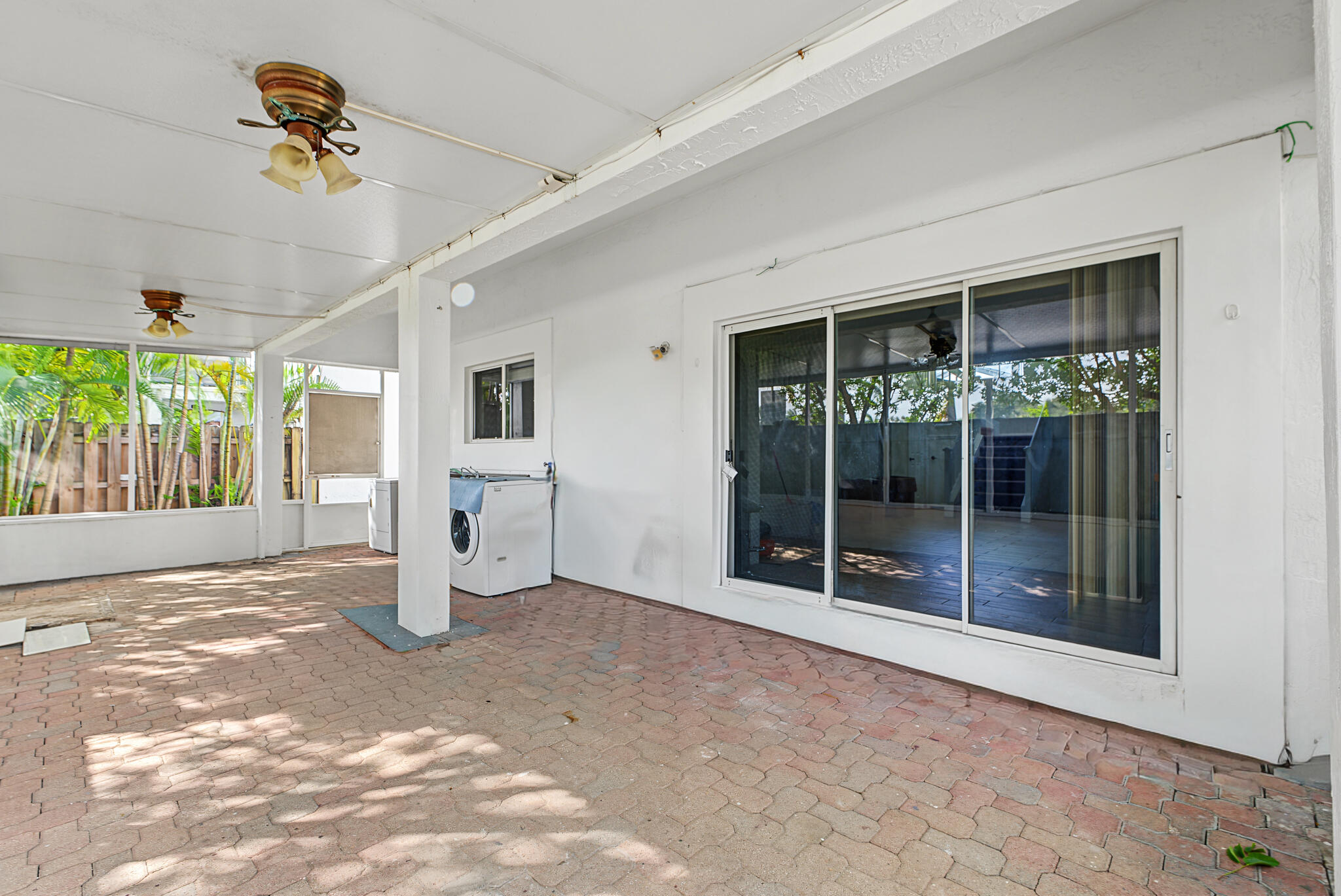 Covered patio featuring paver flooring, dual ceiling-mounted light fixtures, and sliding glass doors