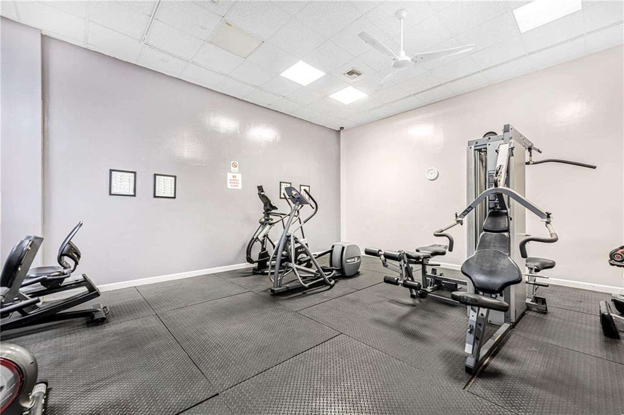 Fitness room featuring resilient rubber flooring, recessed overhead lighting, and a white ceiling fan