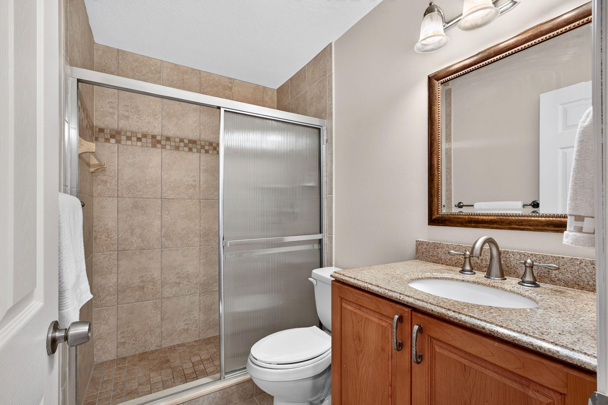 Updated bath with walk-in shower and warm wood vanity