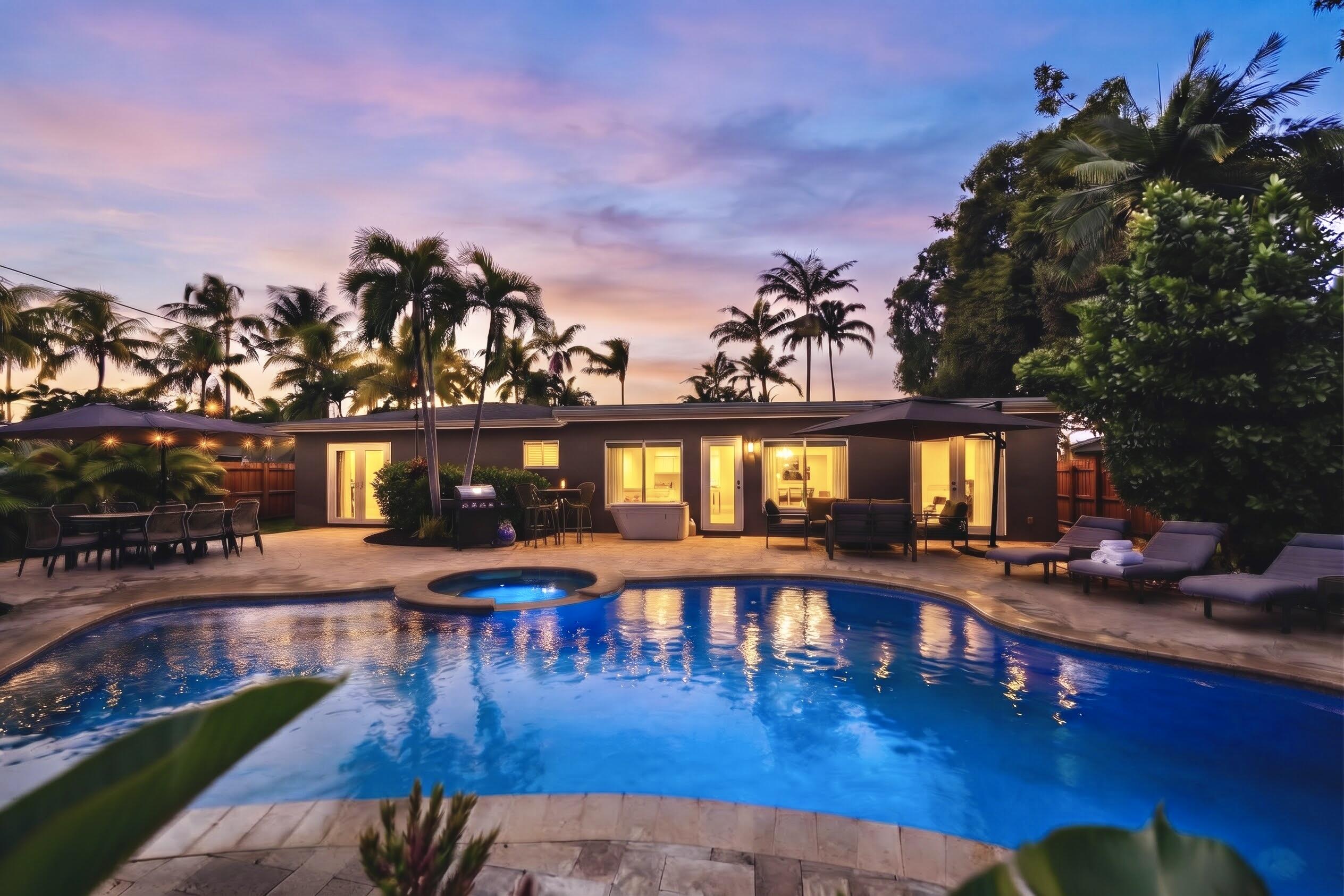 Outdoor living area featuring a swimming pool, integrated spa, expansive stone-paver patio, and mature palm tree landscaping