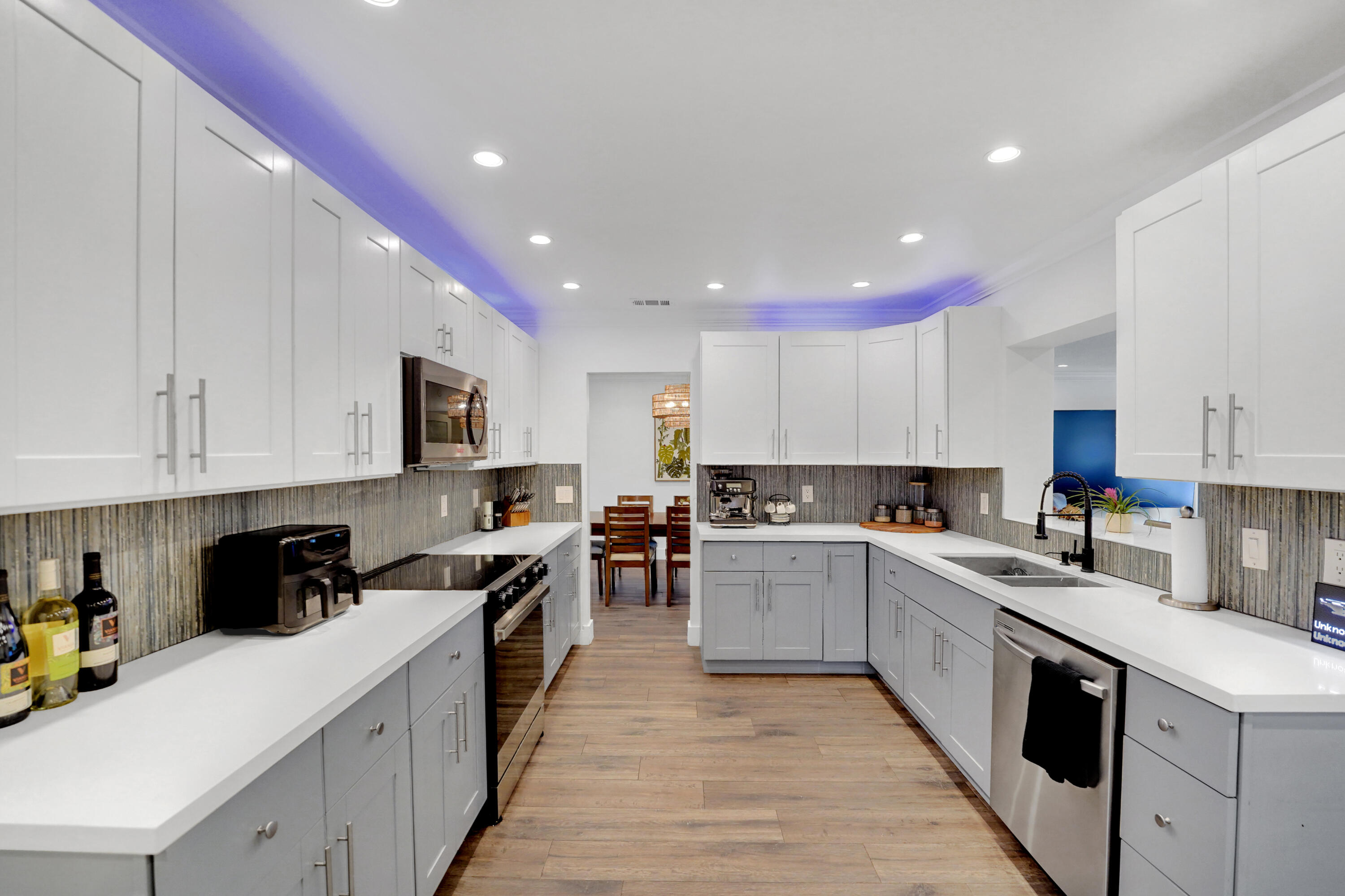 Kitchen featuring two-tone shaker-style cabinetry, quartz countertops, integrated recessed lighting, wood-finish flooring, and a textured backsplash
