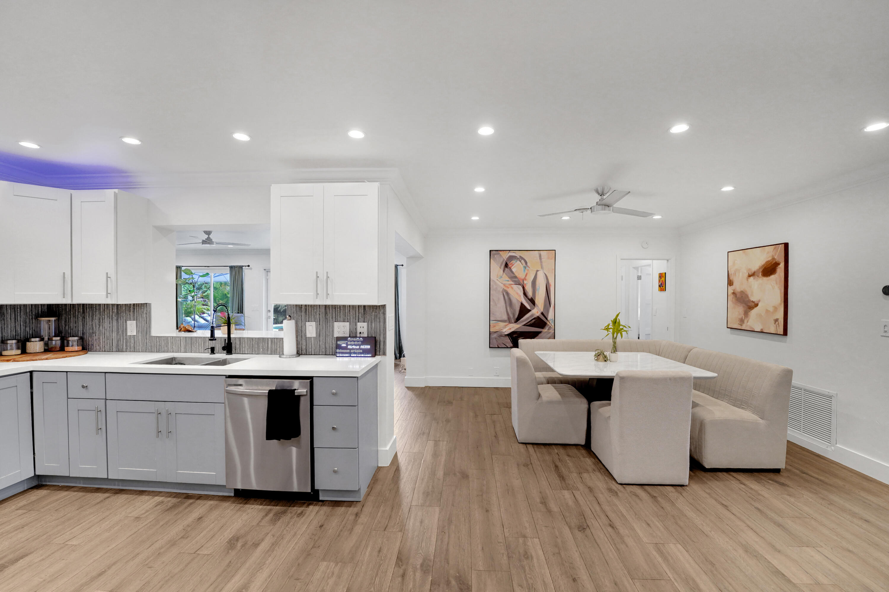 Kitchen featuring white upper cabinetry, grey base cabinetry, light-toned stone-finish countertops, subway tile backsplash, and recessed lighting throughout