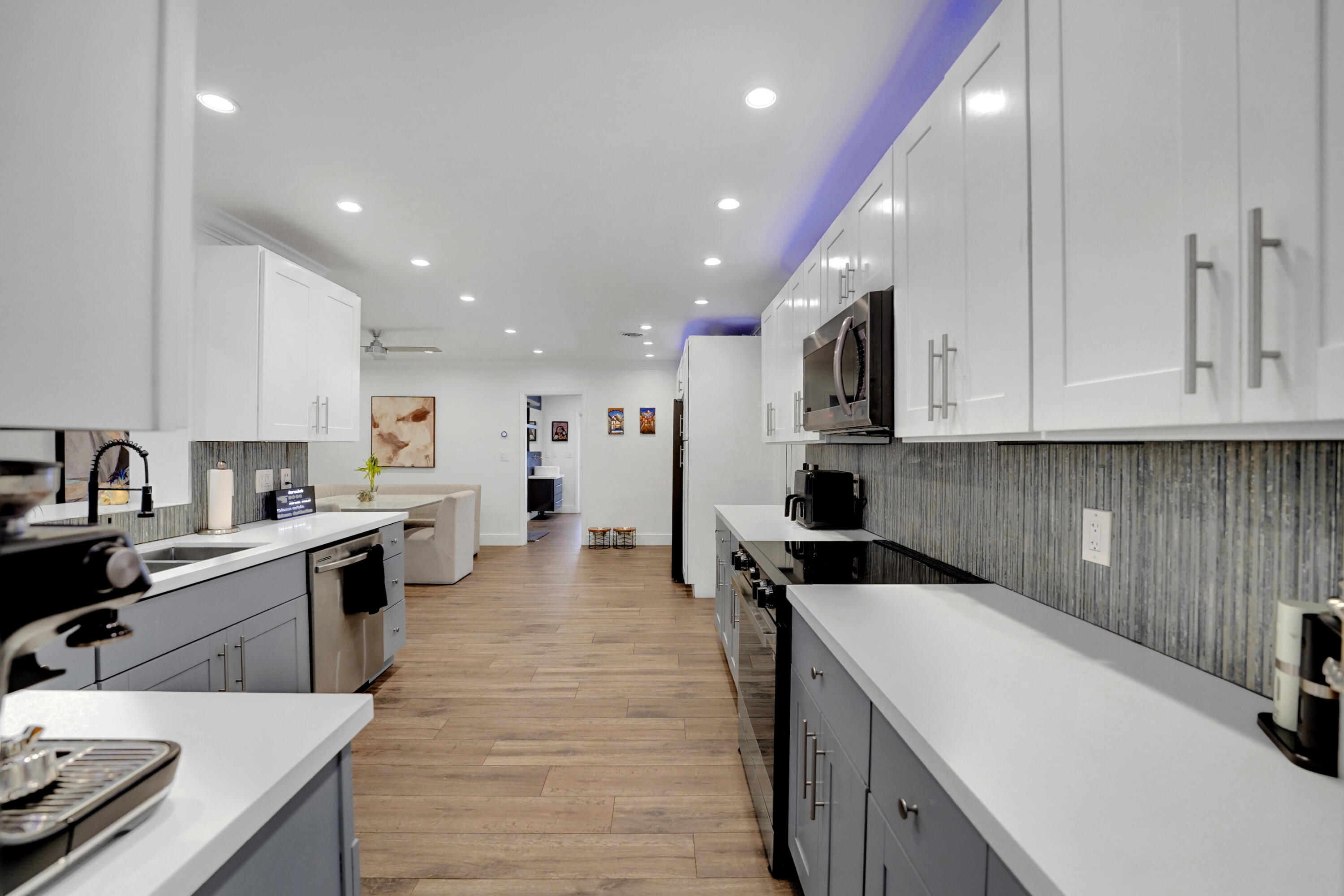 Kitchen featuring white and gray shaker-style cabinetry, white countertops, textured vertical tile backsplash, wood-finish flooring, and recessed ceiling lighting