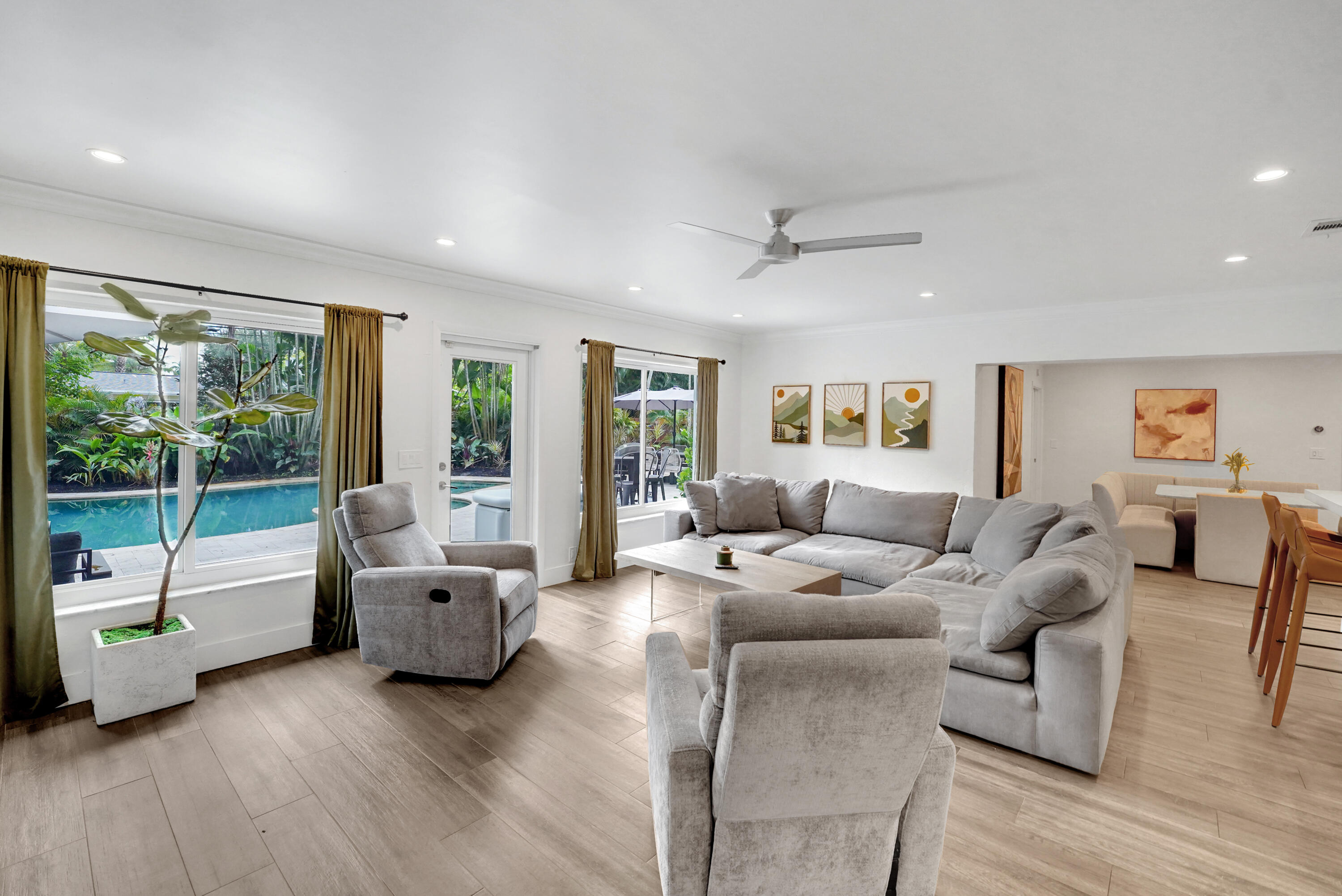 Open-concept living space featuring wood-finish flooring, recessed lighting, a ceiling fan, and large windows providing natural light