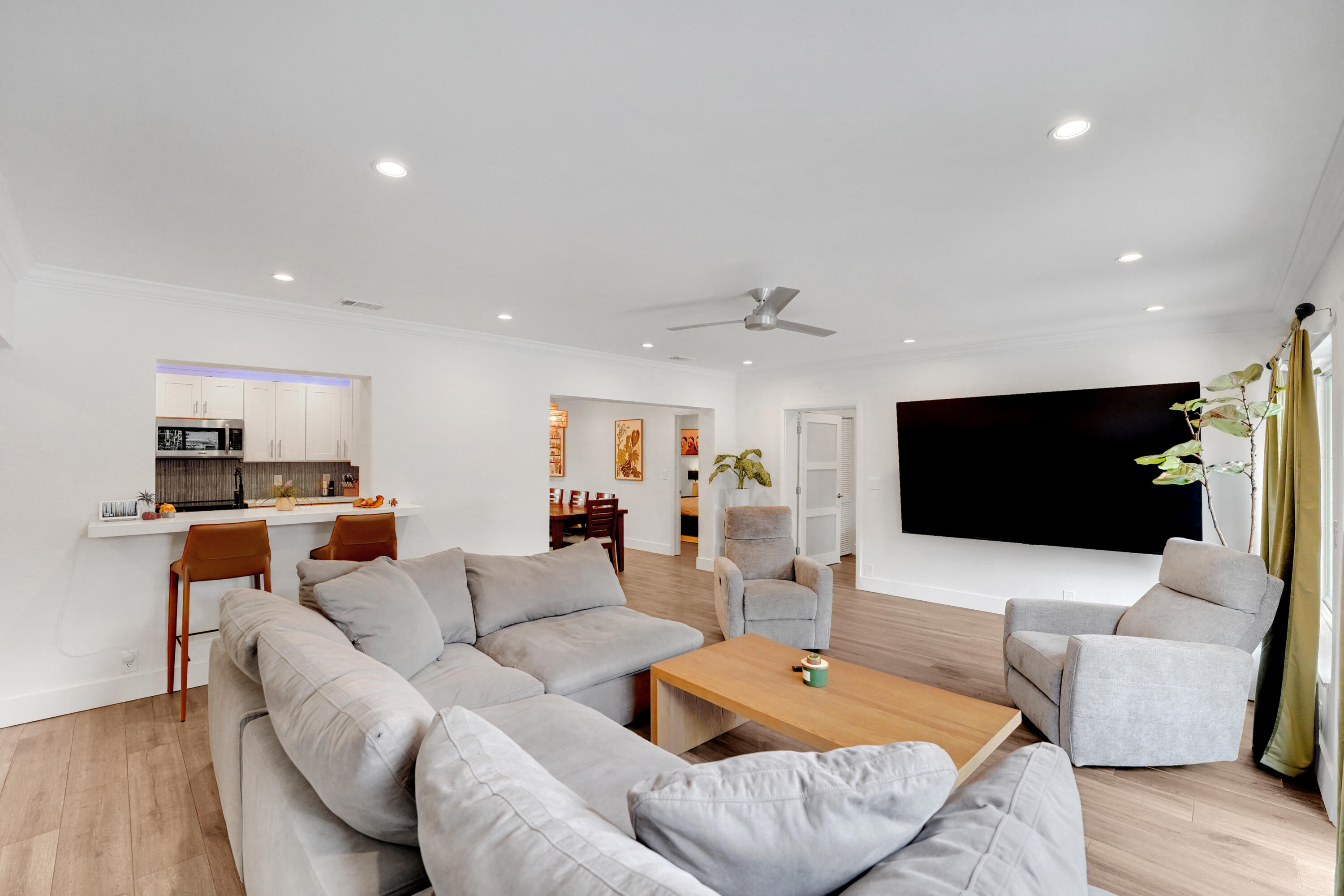 Open-concept living space recessed lighting, crown molding, a ceiling fan, and a breakfast bar with built-in cabinetry
