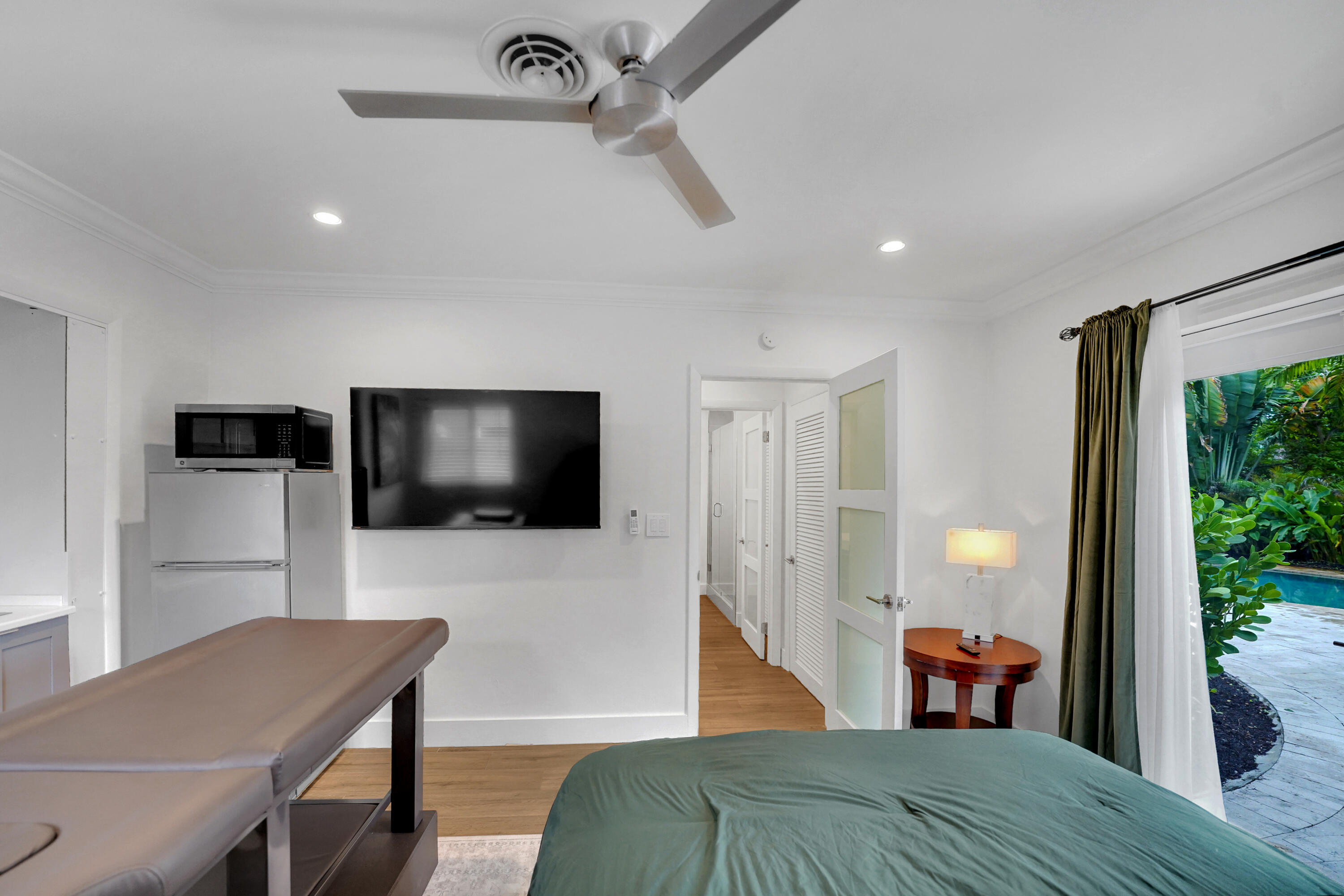 Modern interior featuring wood-finish flooring, recessed lighting, a ceiling fan with integrated lighting, and a glass-paneled entry door
