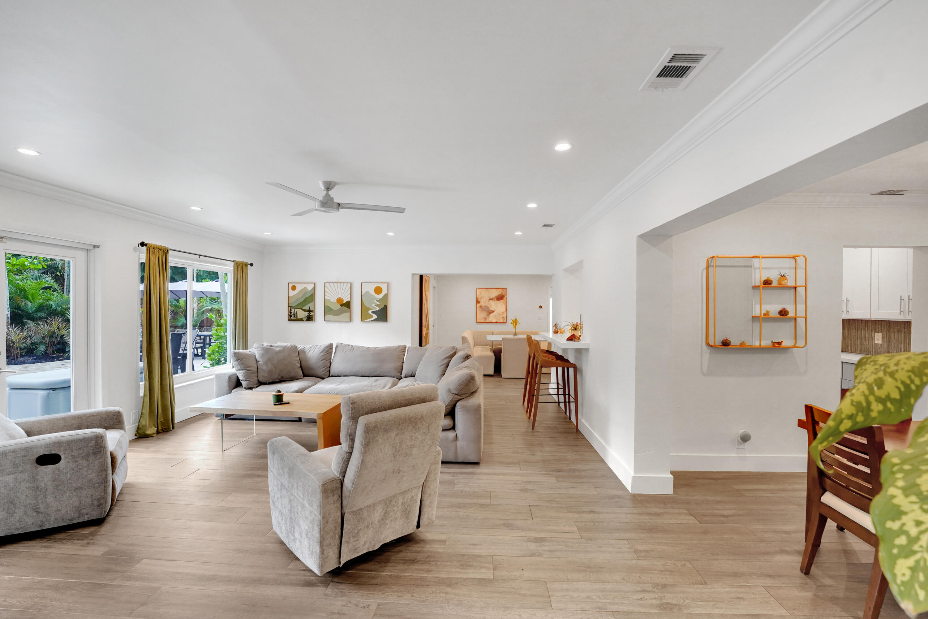 Open-concept living space featuring wood-finish flooring, recessed lighting, crown molding, a ceiling fan, and a built-in breakfast bar