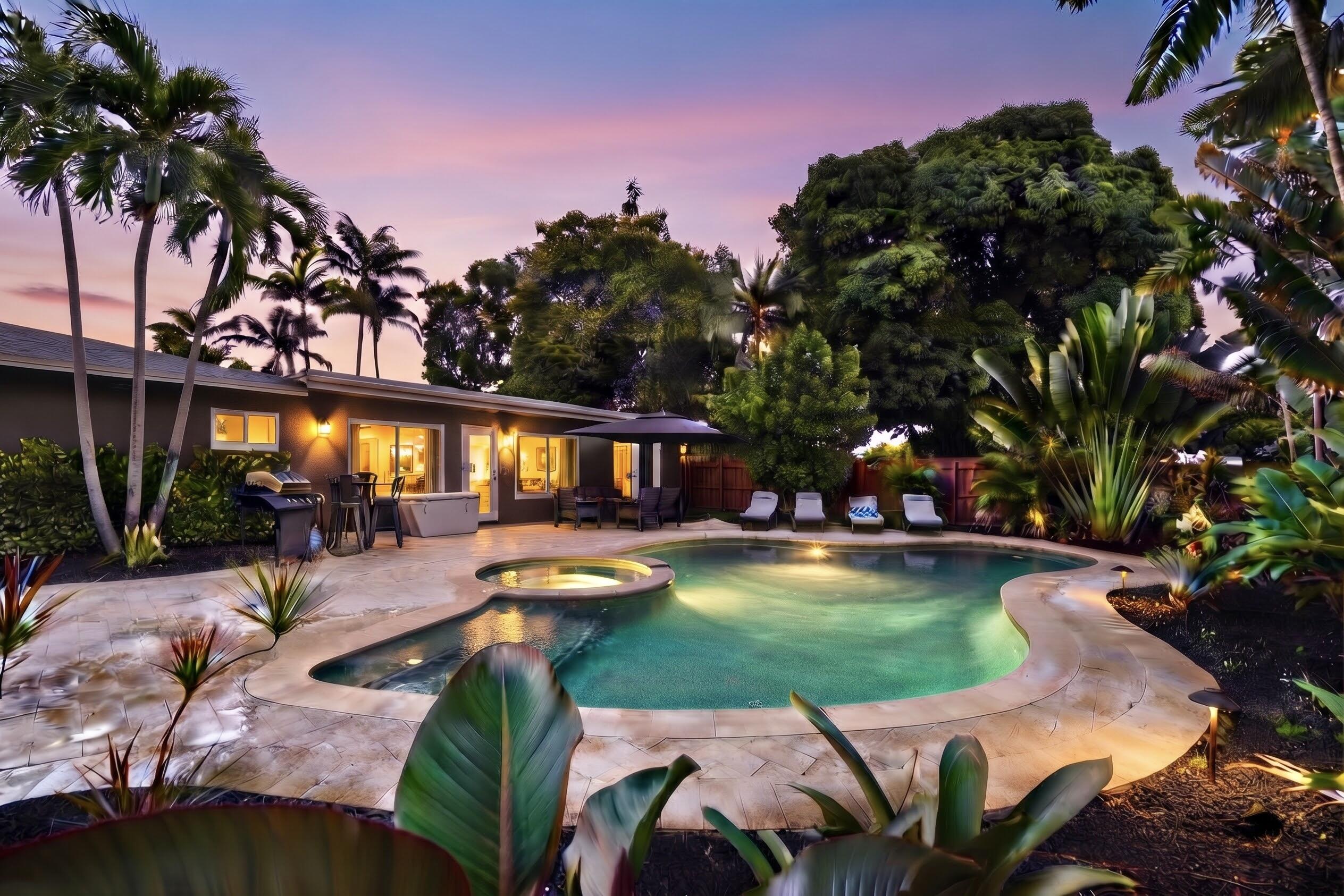 Custom-shaped in-ground pool featuring an integrated spa, stone paver decking, lush tropical landscaping, and mature foliage