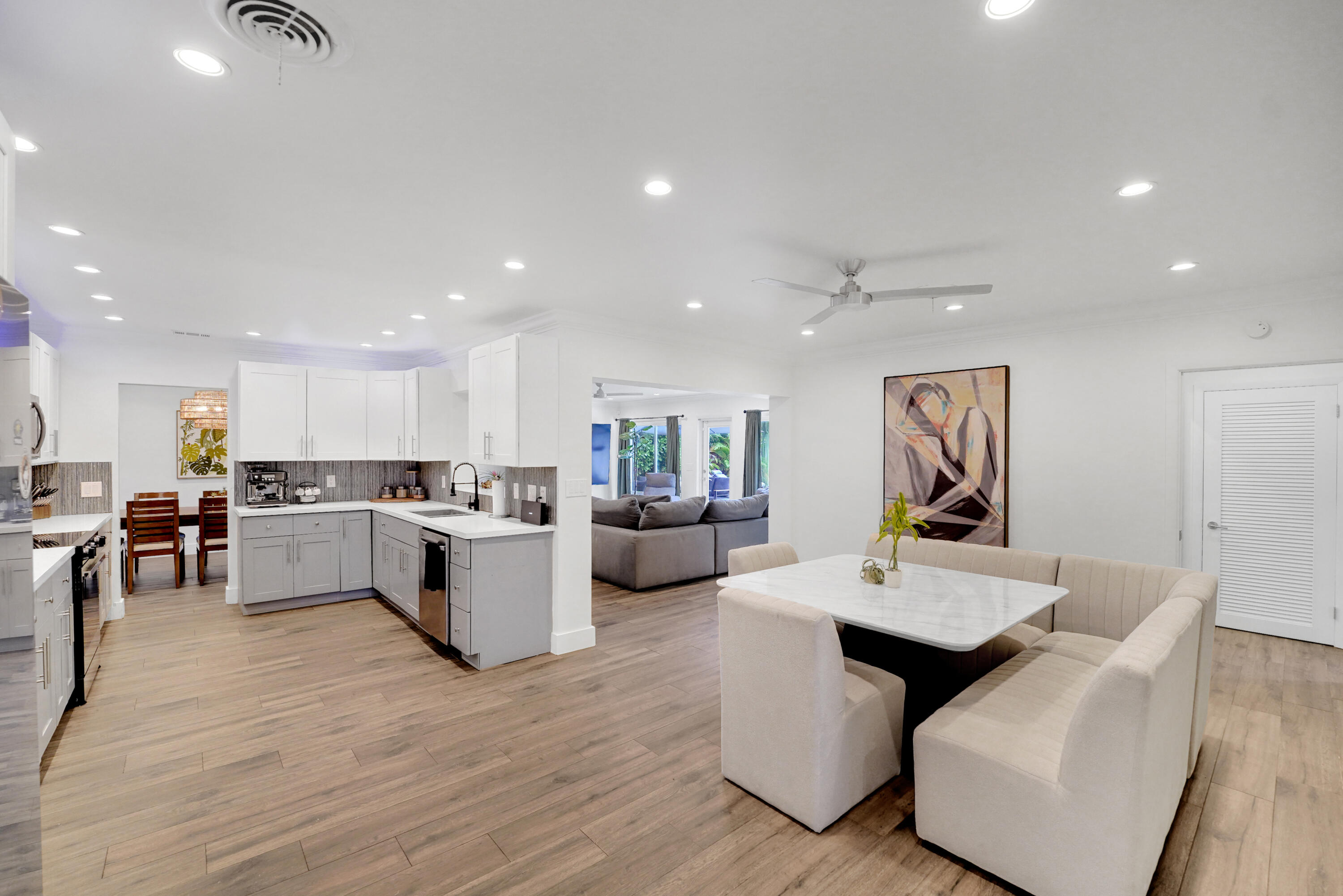 Open-concept kitchen featuring two-tone cabinetry, stone-finish countertops, recessed lighting.