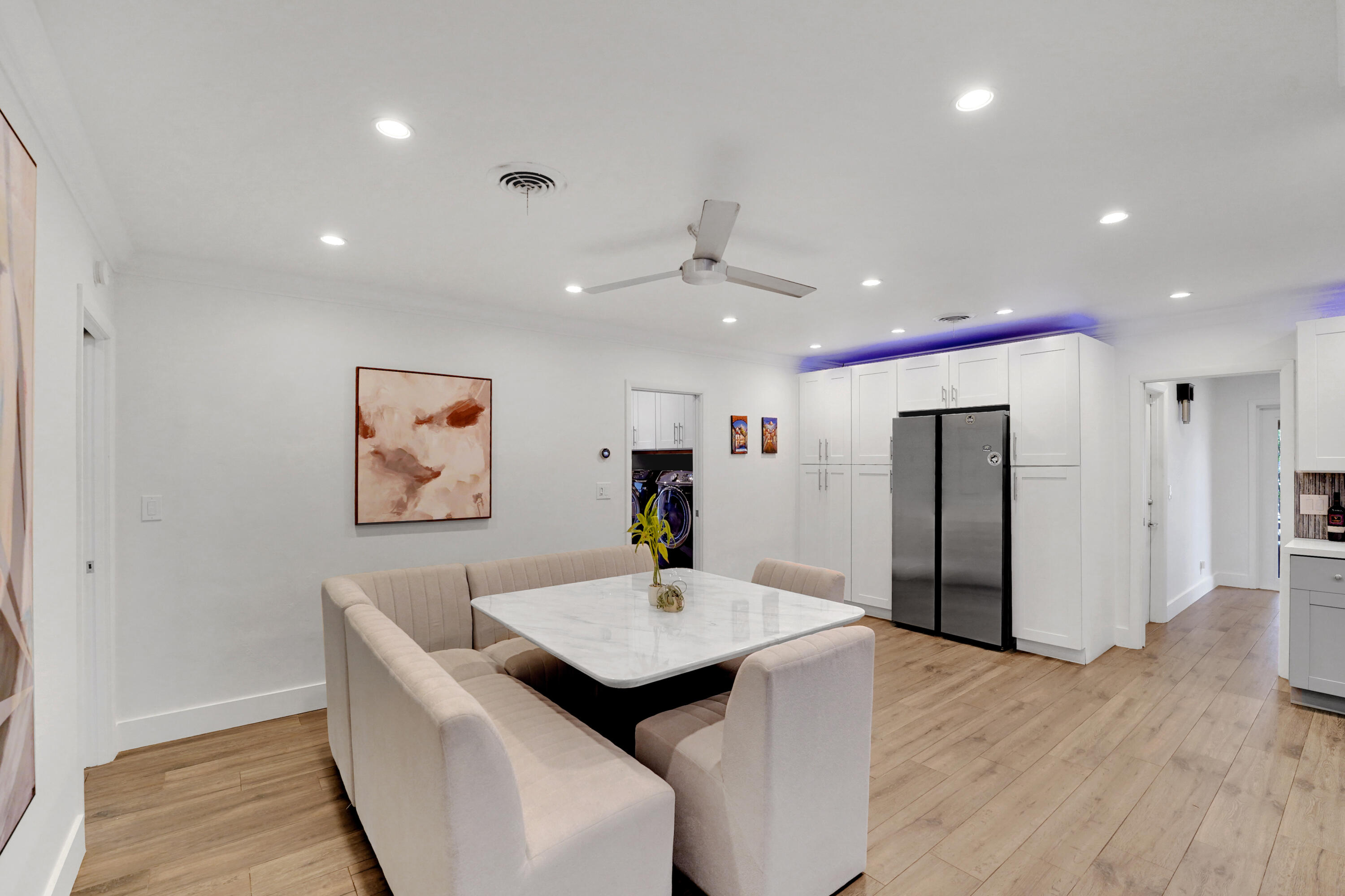 Wood-finish flooring, recessed lighting, ceiling fan, and floor-to-ceiling white cabinetry with a stainless steel side-by-side refrigerator