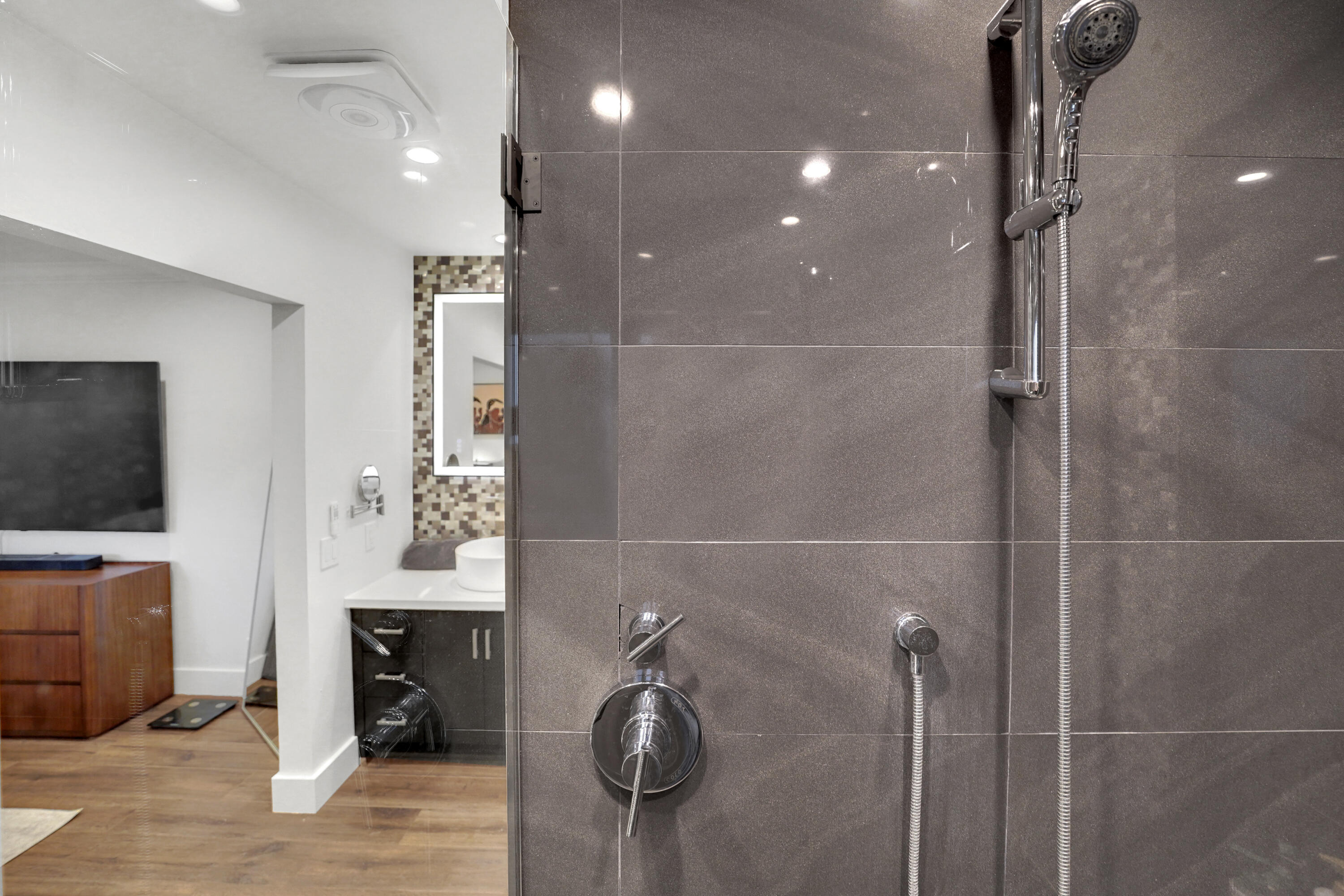 Shower enclosure featuring large-format grey tile, a chrome handheld shower head, and integrated single-handle temperature control