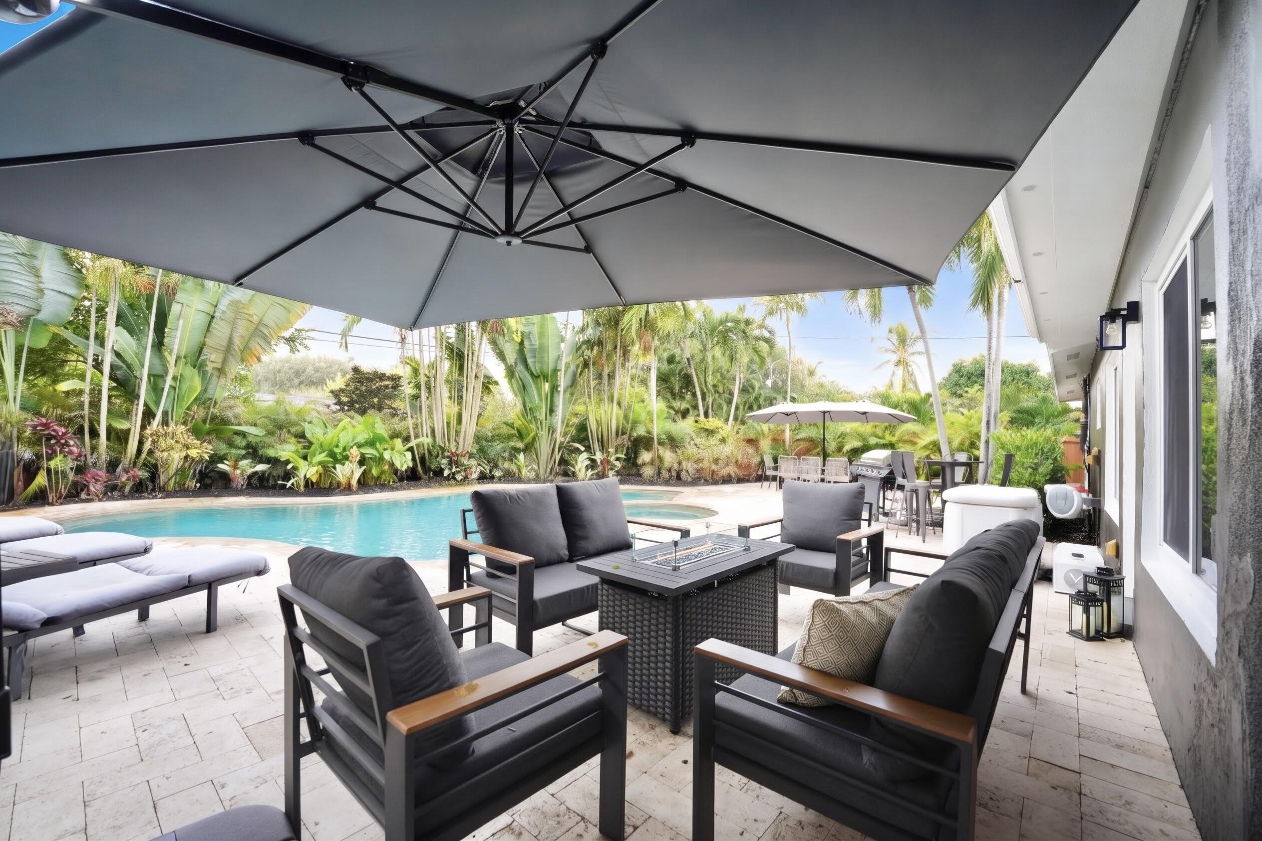 Outdoor patio featuring stone paver flooring, custom in-ground pool, and mature palm landscaping