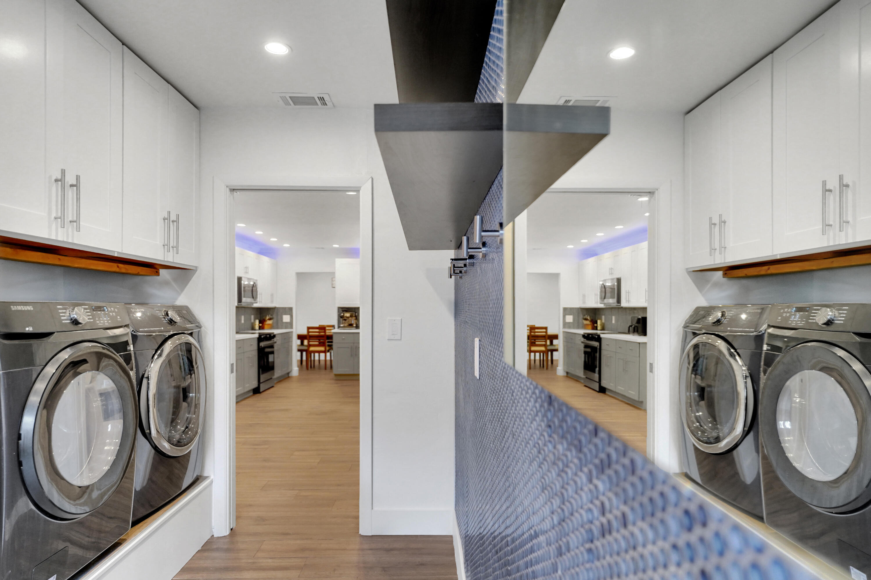 Laundry room featuring crisp white cabinetry with satin nickel pulls, a textured blue accent wall with built-in shelving.