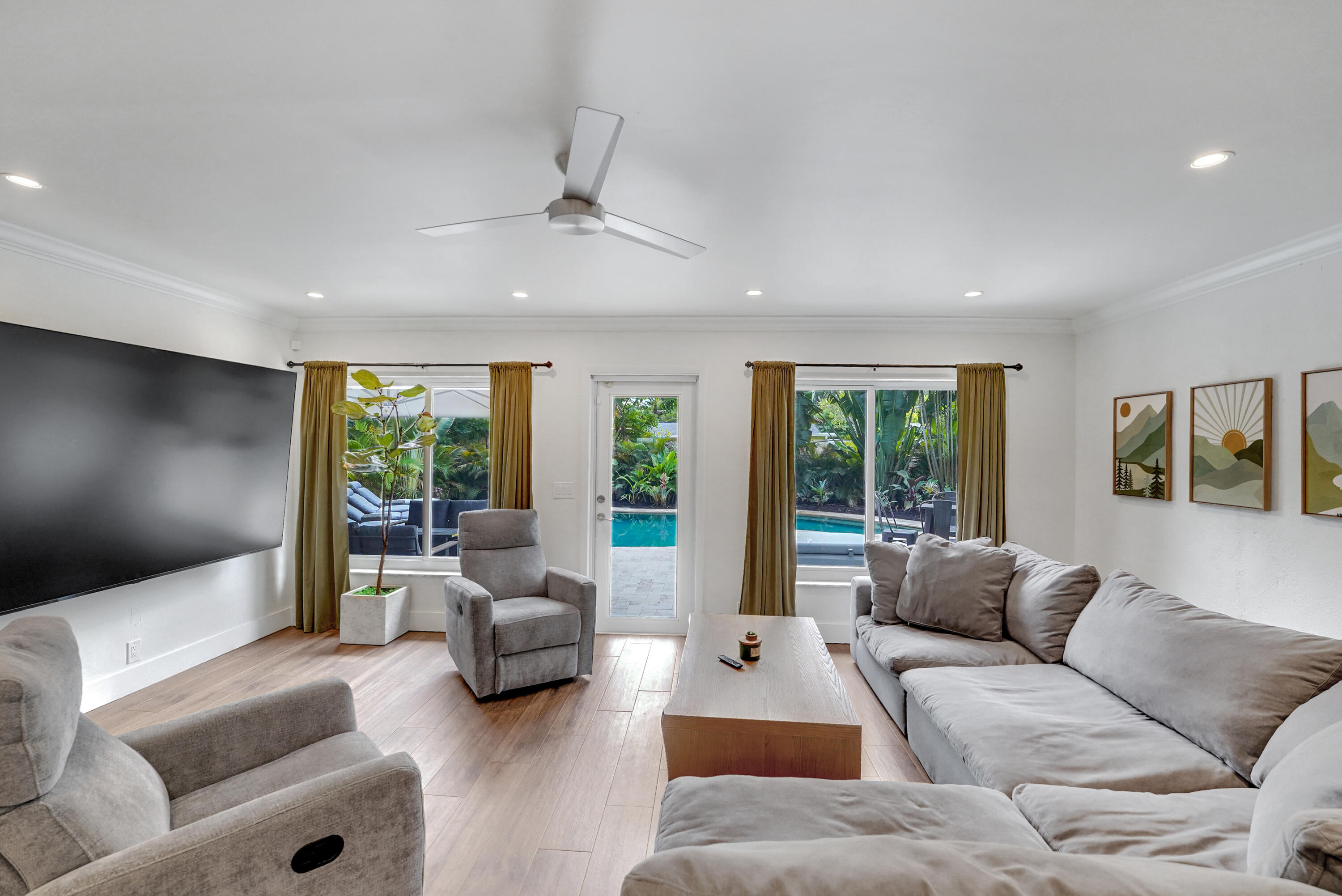 Living area recessed lighting, a modern ceiling fan, and access to a rear outdoor pool area via a glass-paneled door