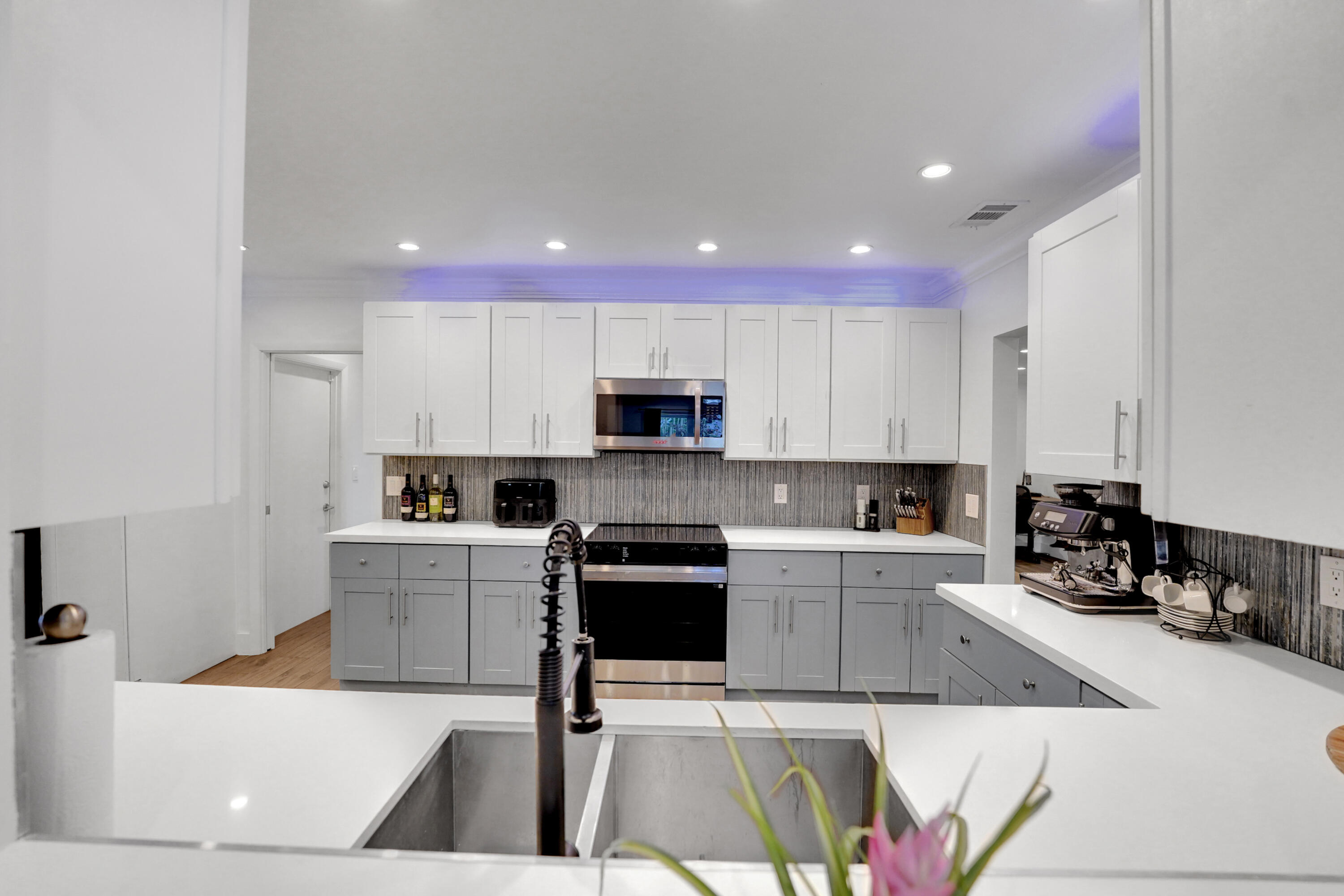 Kitchen featuring two-tone cabinetry, white countertops, stainless steel appliances, recessed ceiling lighting, and a dual-basin stainless steel sink with a high-arch pull-down faucet