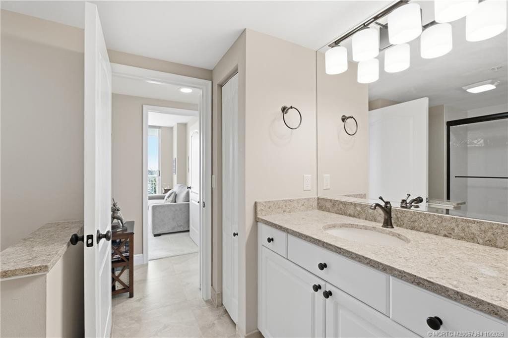 Additional view of the primary bathroom showcasing granite countertops, white cabinetry, and updated lighting.