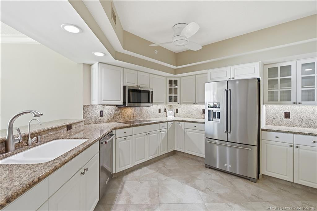 Beautifully appointed kitchen featuring granite countertops, white cabinetry, and a full suite of stainless-steel appliances.